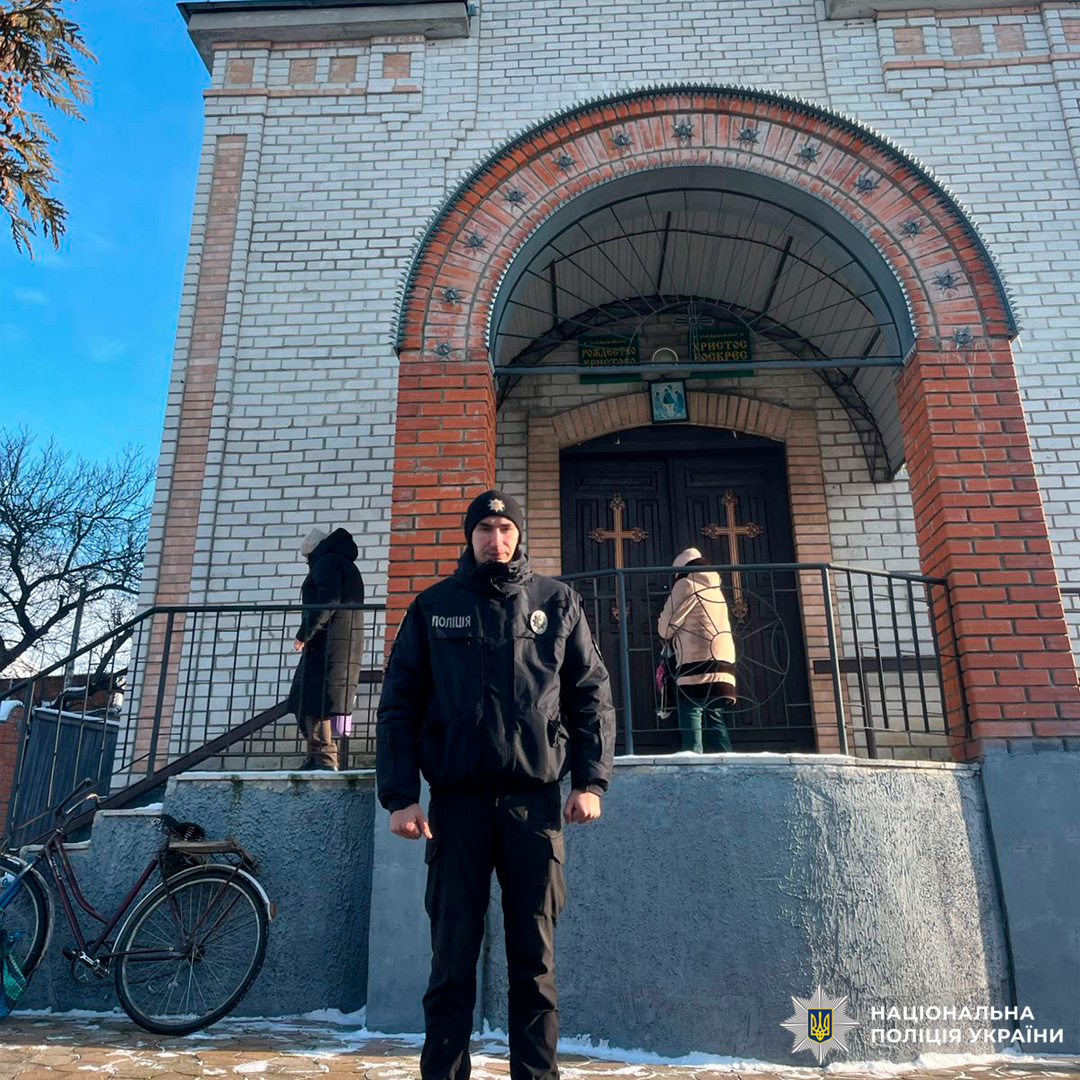 Поліцейський у тактичному спорядженні біля храму взимку.