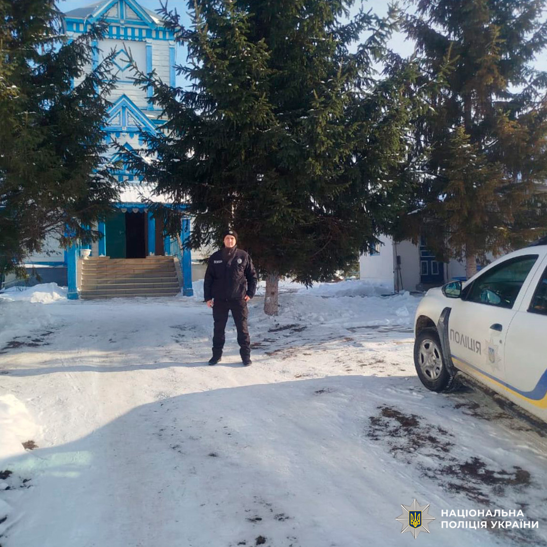 Поліцейський у тактичному спорядженні біля храму взимку.