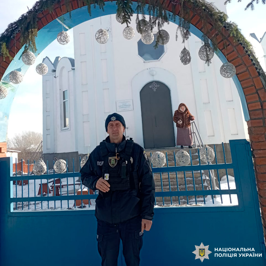 Поліцейський у тактичному спорядженні біля храму взимку.