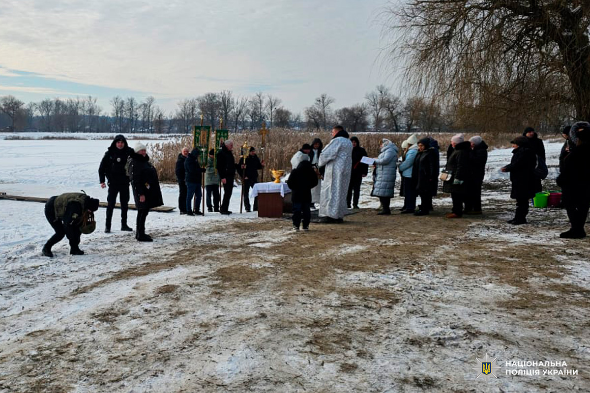 Громада біля водойми взимку, поліцейський забезпечує порядок.