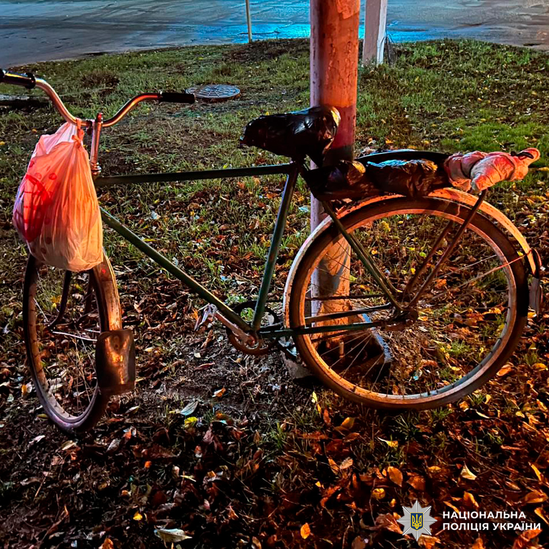 Поліція зафіксувала зелений велосипед, пристебнутий до стовпа на узбіччі. На кермі висить пакет, сидіння та багажник вкриті чорними й прозорими поліетиленовими обгортками.