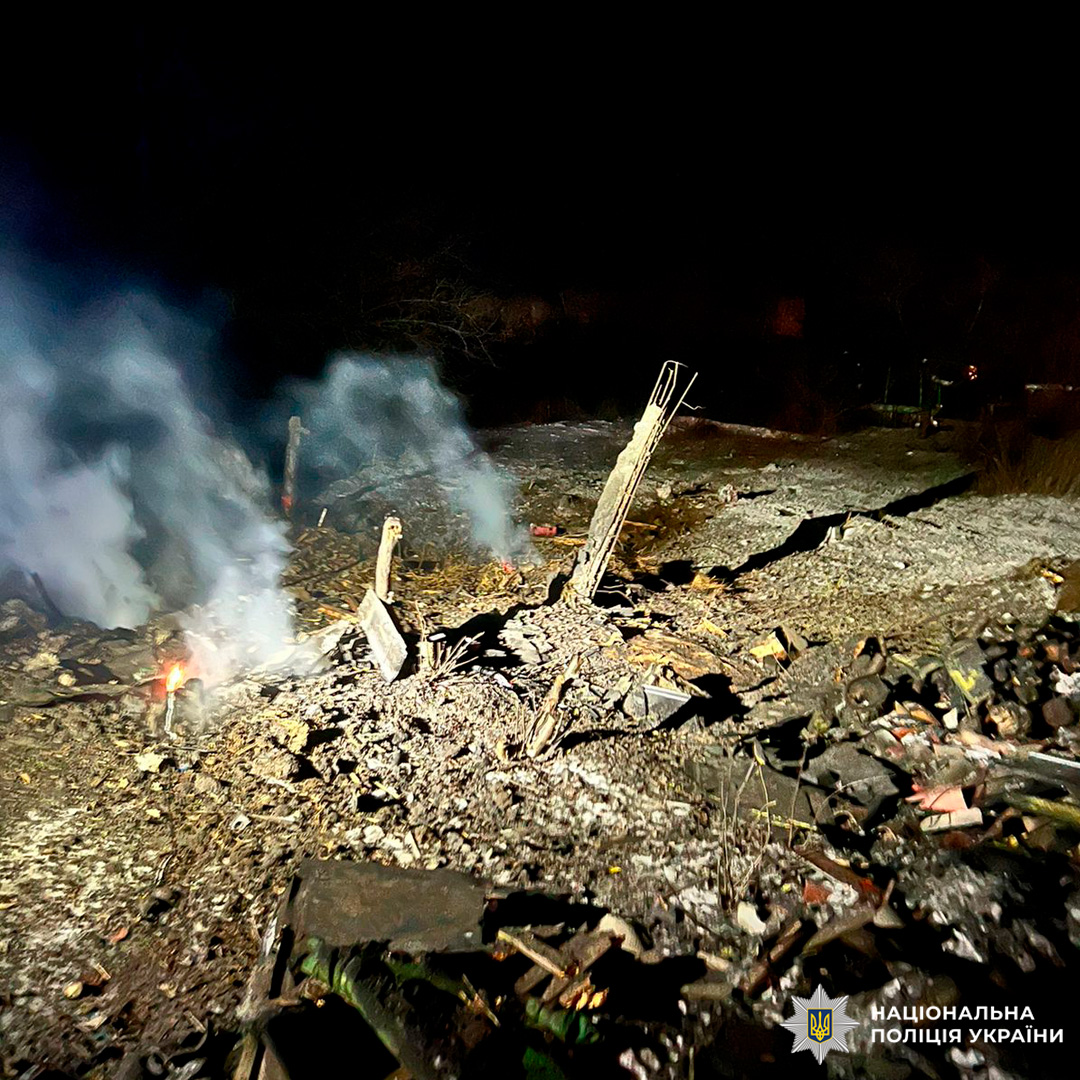 Поліція задокументувала наслідки вибуху: пошкоджена територія з уламками та осередками диму, освітлена прожекторами.