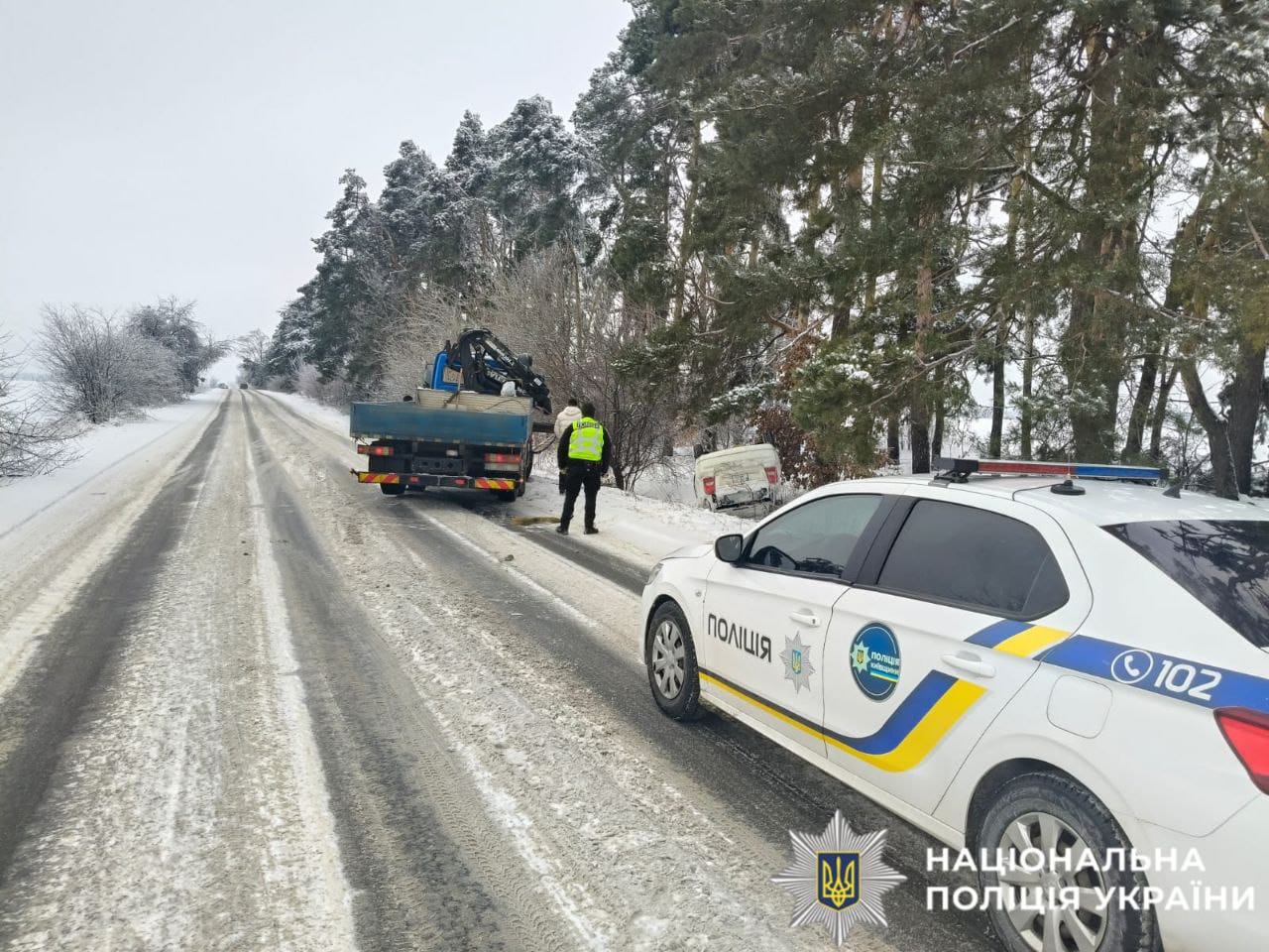 На фото зображено як поліцейські допомагають водієві.