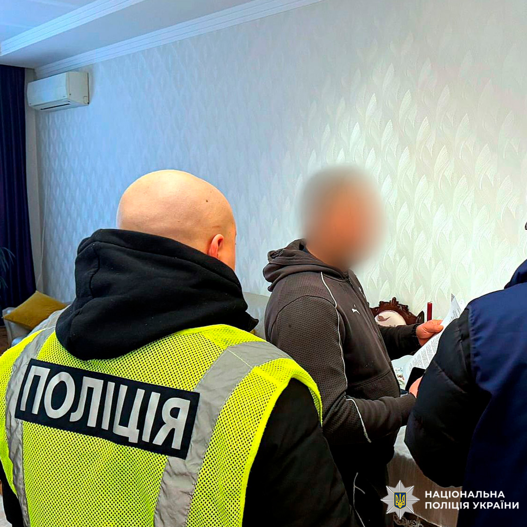 Поліцейський у жилеті «Поліція» проводить офіційну розмову з людиною, яка затримана.