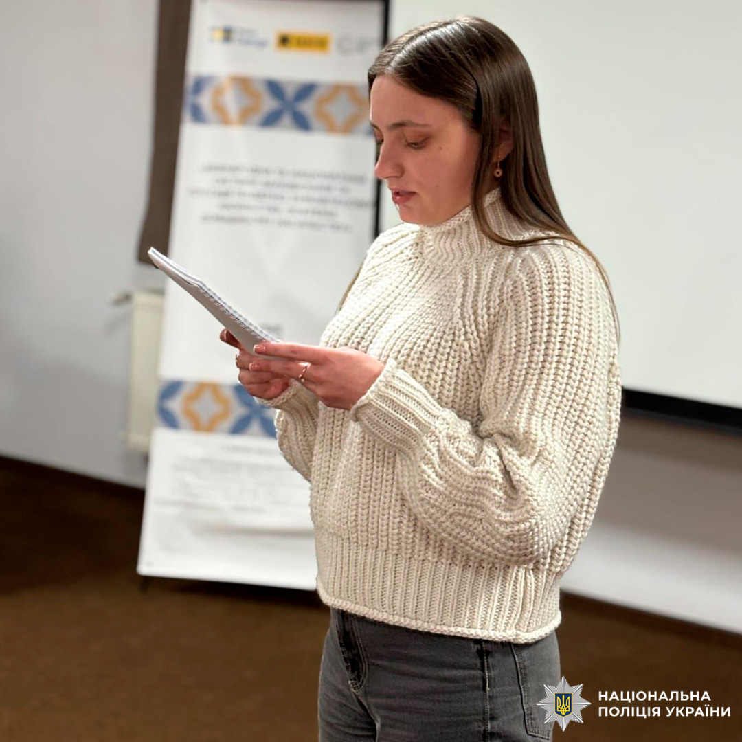 Під час семінару учасник виступає з нотатками, а на тлі видно банер із темою про права людини в роботі поліції.