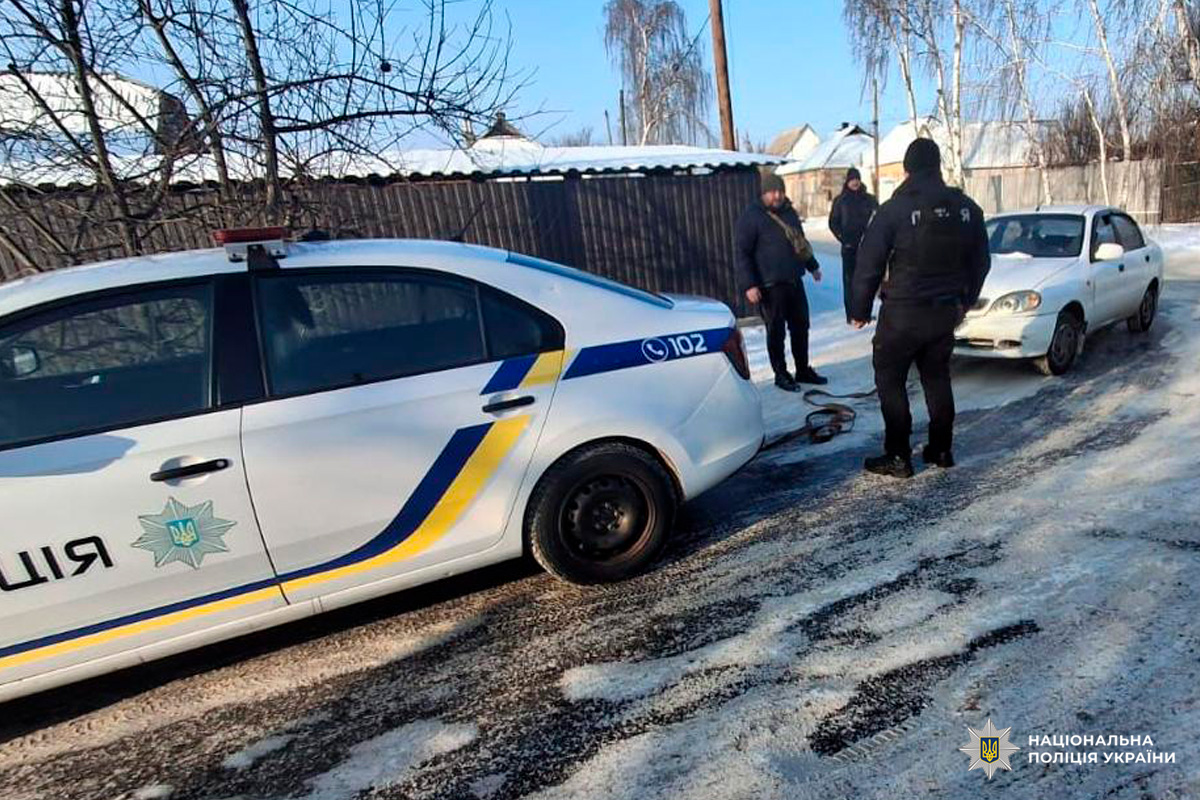 Поліцейський автомобіль із написом «ПОЛІЦІЯ» та номером 102 буксирує цивільну машину за допомогою троса.