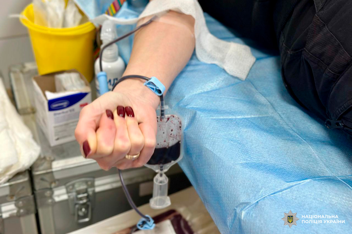 Поліцейський у формі лежить на медичному ліжку та здає кров у клінічних умовах.