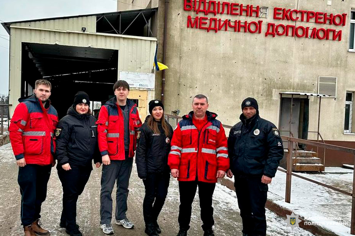 Група правоохоронців і медиків позує біля входу до відділення екстреної допомоги.