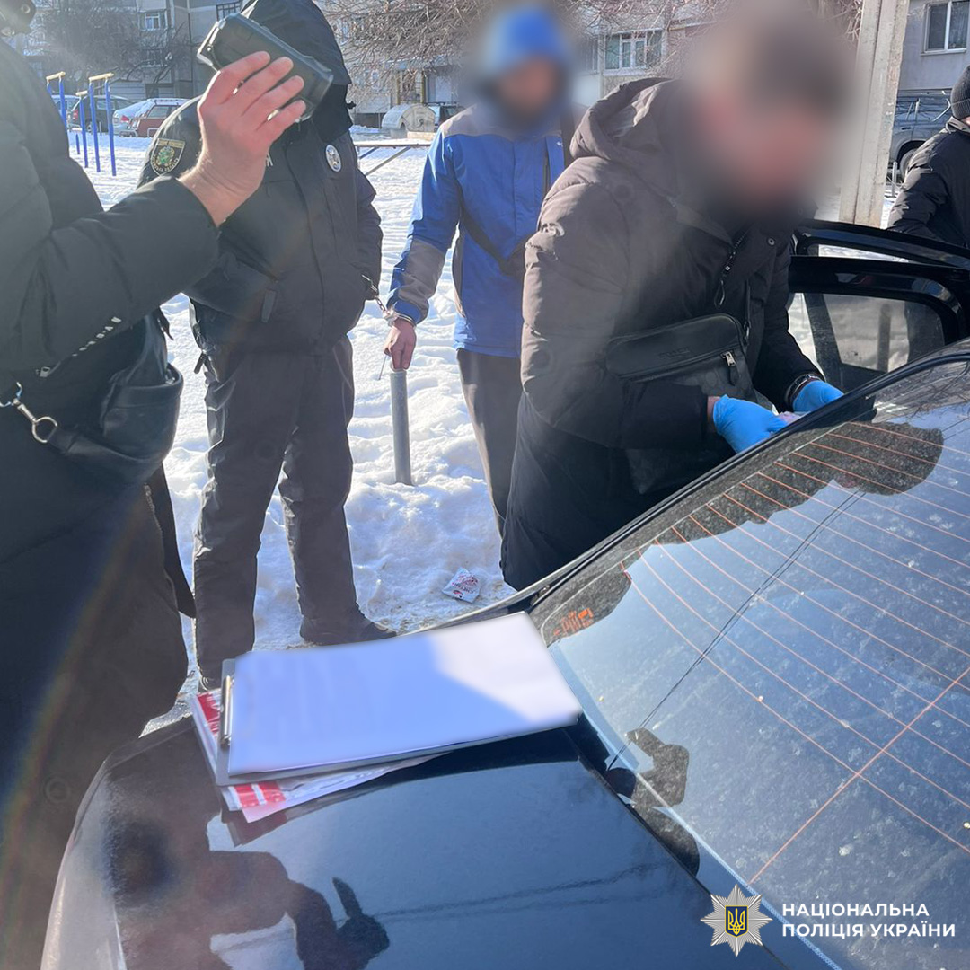 Поліцейські у формі проводять слідчі дії біля машини, на багажнику документи.