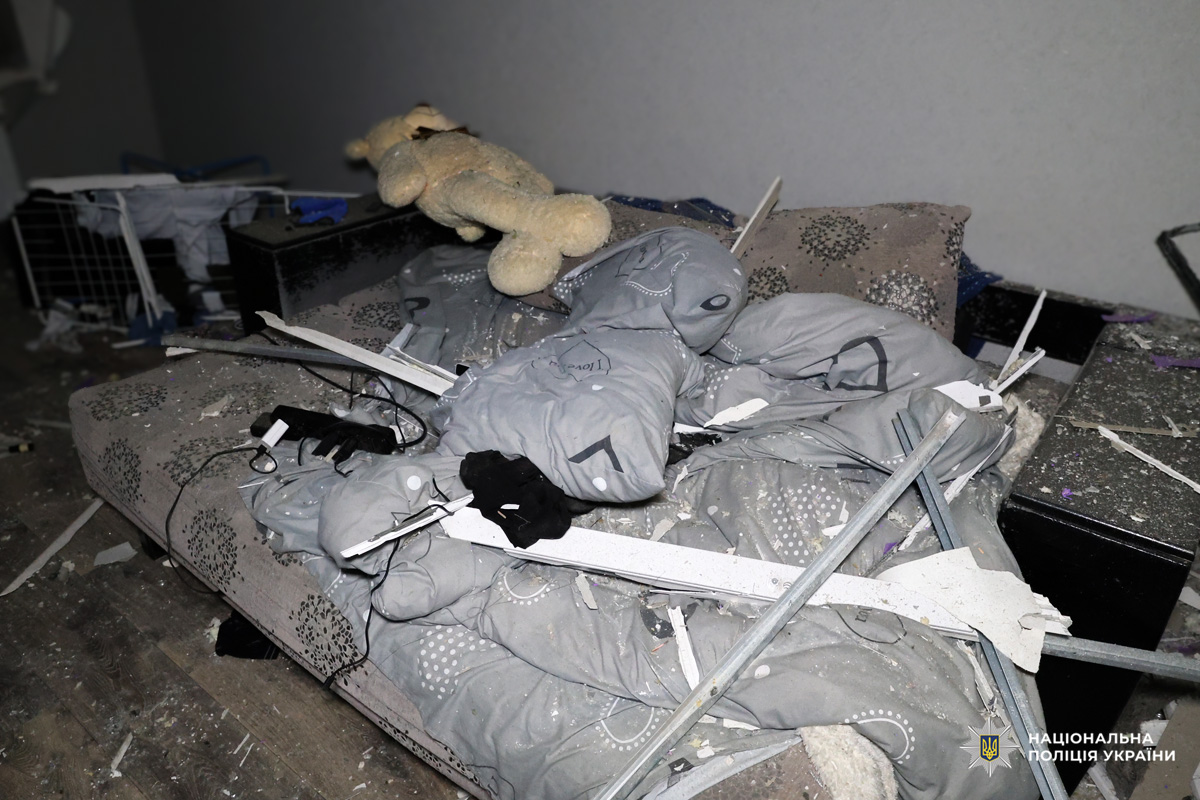 Пошкоджена кімната з розбитими меблями та сміттям.