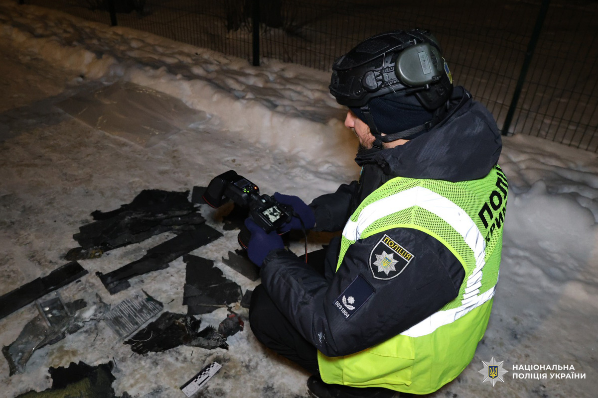 Поліцейський фотографує уламки на засніженій території.