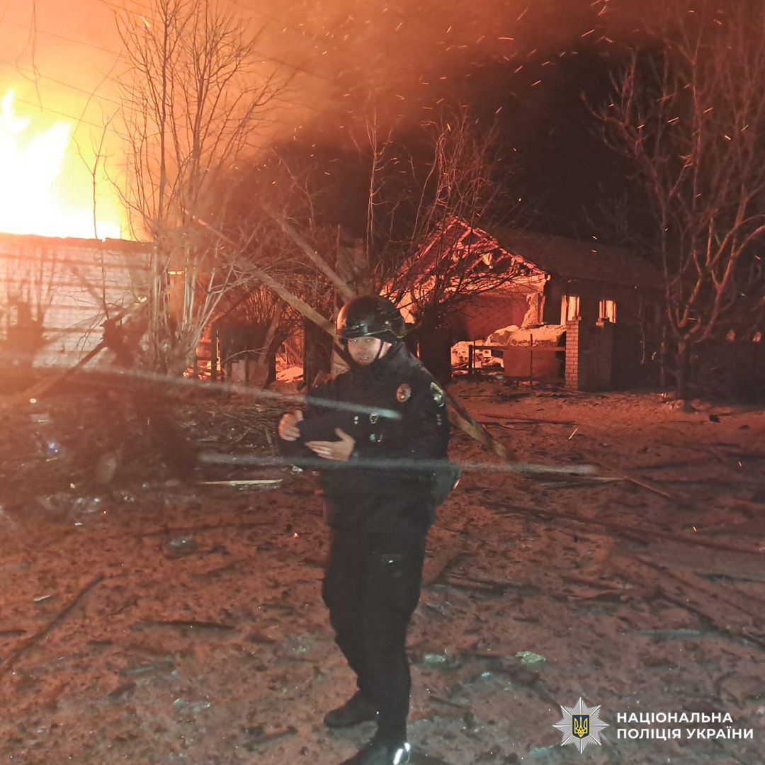 Нічна пожежа: будівля у вогні, поліцейський у спорядженні на передньому плані.