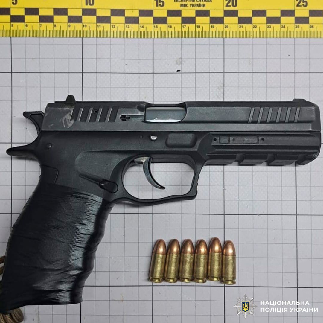 Вилучений пістолет із обмотаною рукояткою та сім набоями, розташованими на вимірювальній сітці.