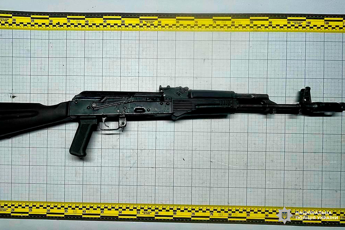 Вилучена штурмова гвинтівка чорного кольору, розташовану на вимірювальній сітці.