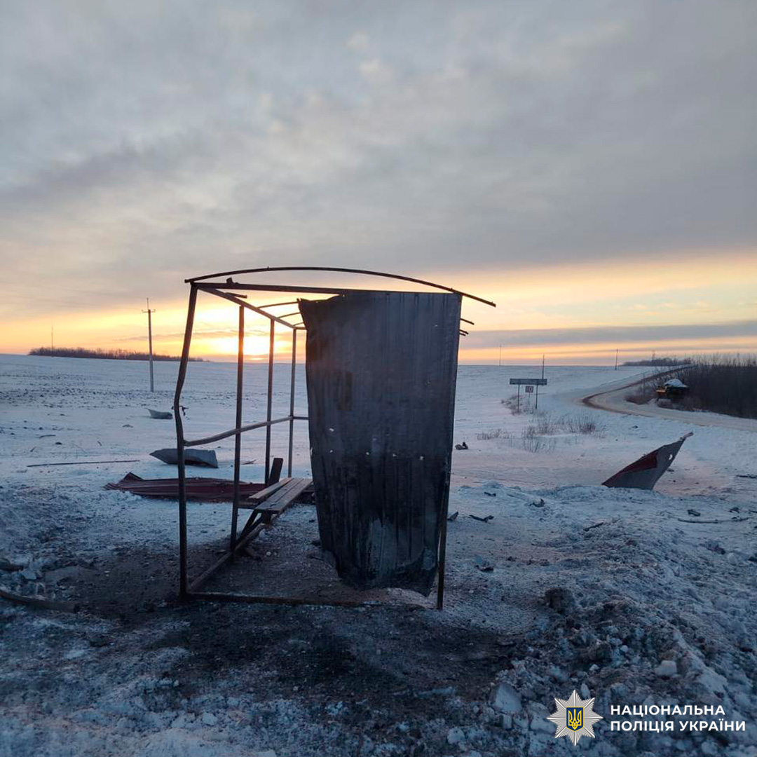 Зруйнована автобусна зупинка на засніженій дорозі.