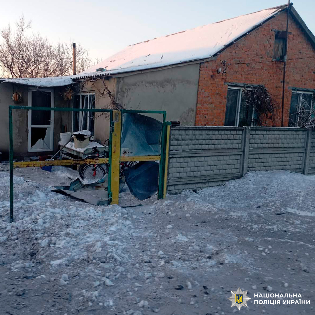 Пошкоджений житловий будинок із розбитими вікнами та зламаними воротами, на даху сніг.