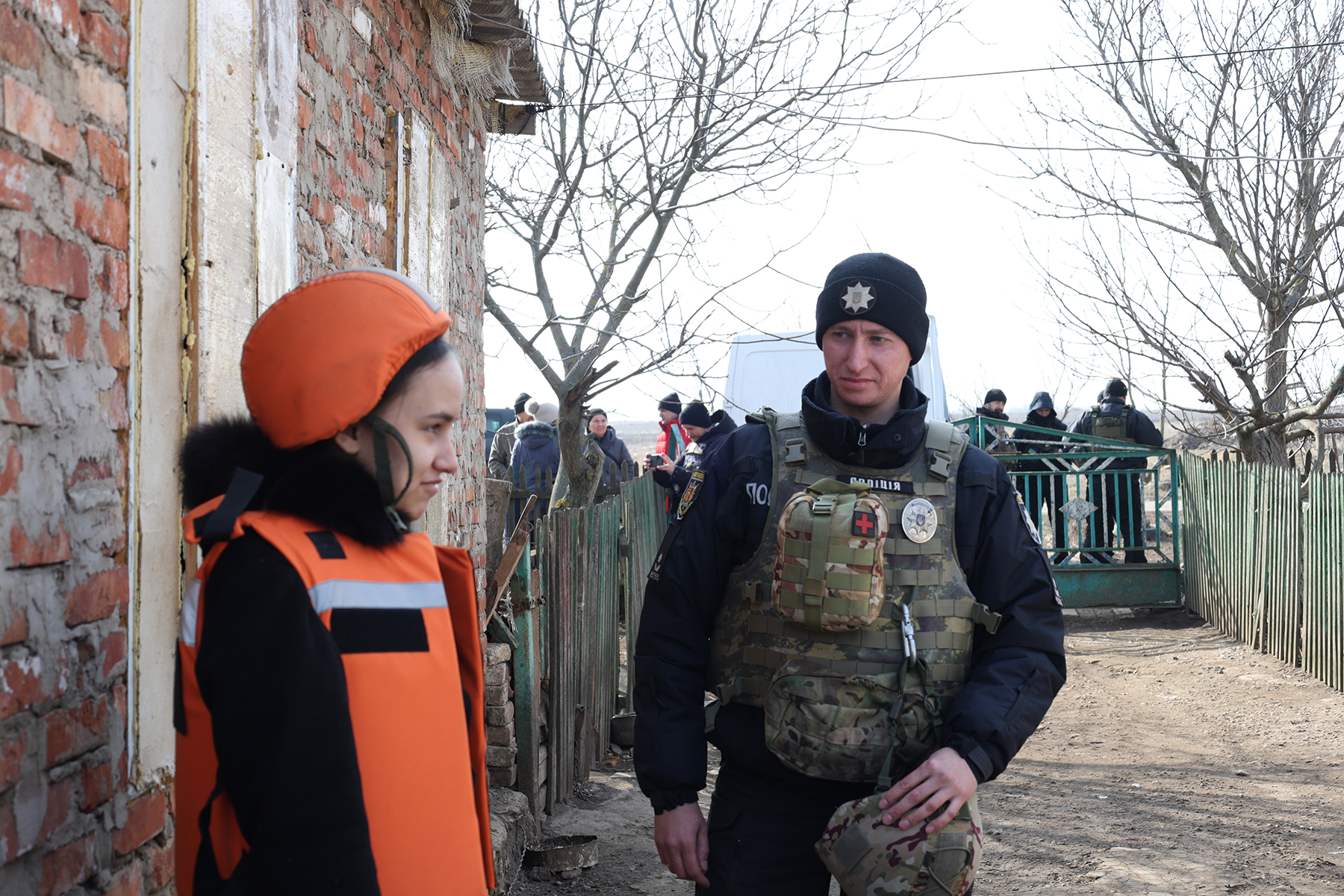 Поліцейський стоїть поруч з останньою дитиною, евакуйованою з села Омельник Пологівського району. Березень 2025 року.