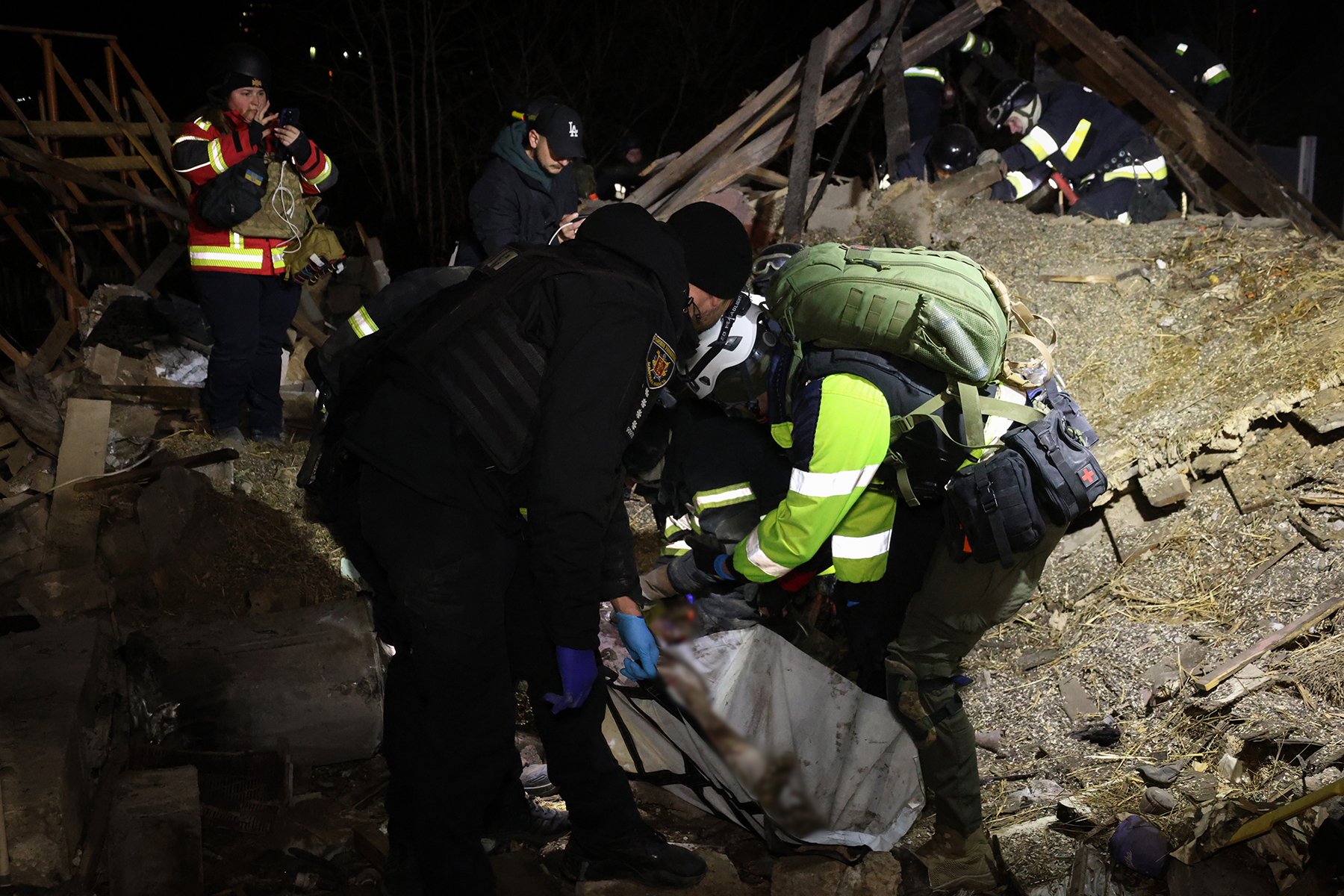 Поліцейський допомагає дістати з-під руїн тіло людини, загиблої внаслідок ракетного удару росіян по обласному центру. Березень 2025 року.