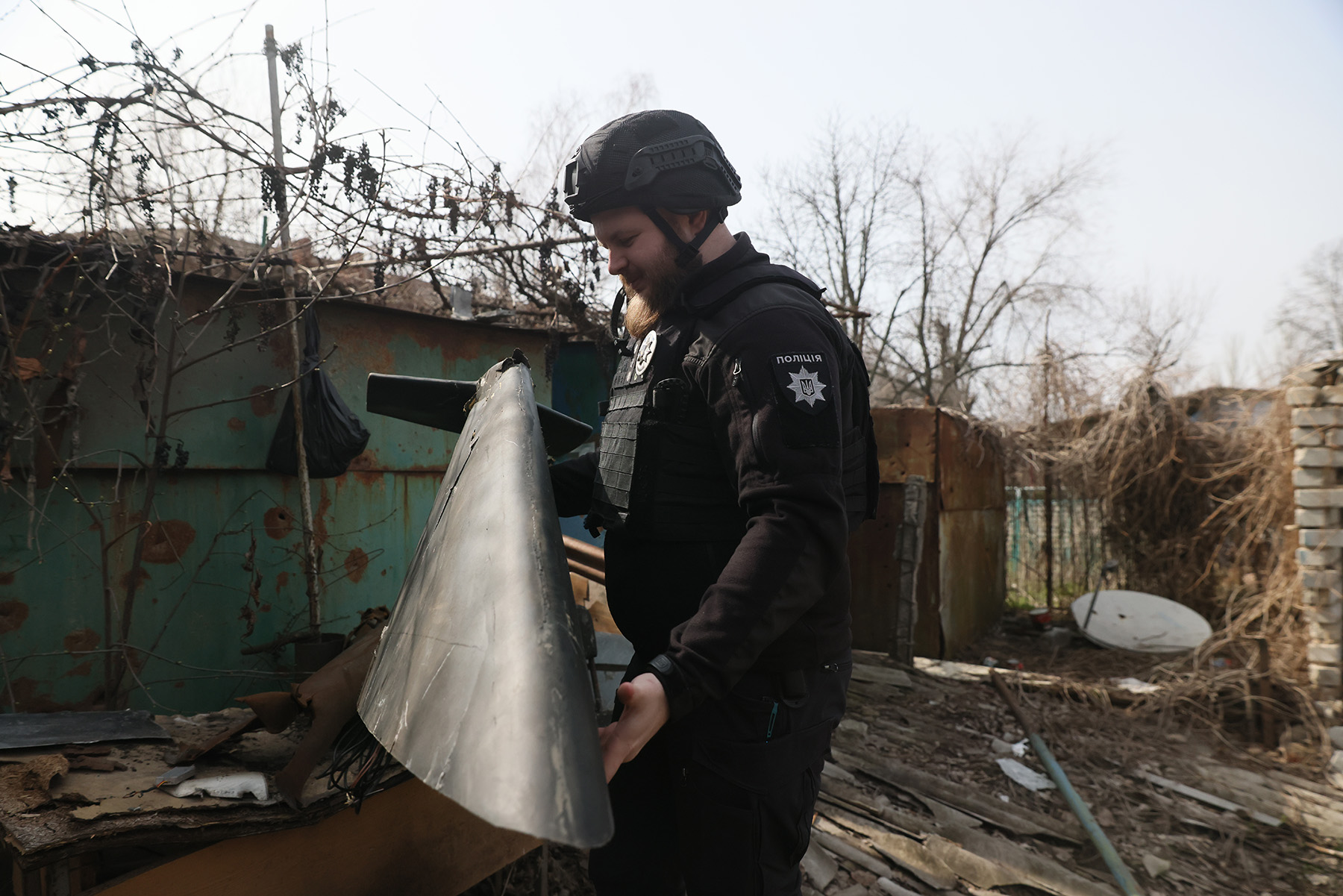 Поліцейський офіцер громади тримає в руках частину ворожого ударного безпілотника. Місто Гуляйполе. Березень 2025 року.