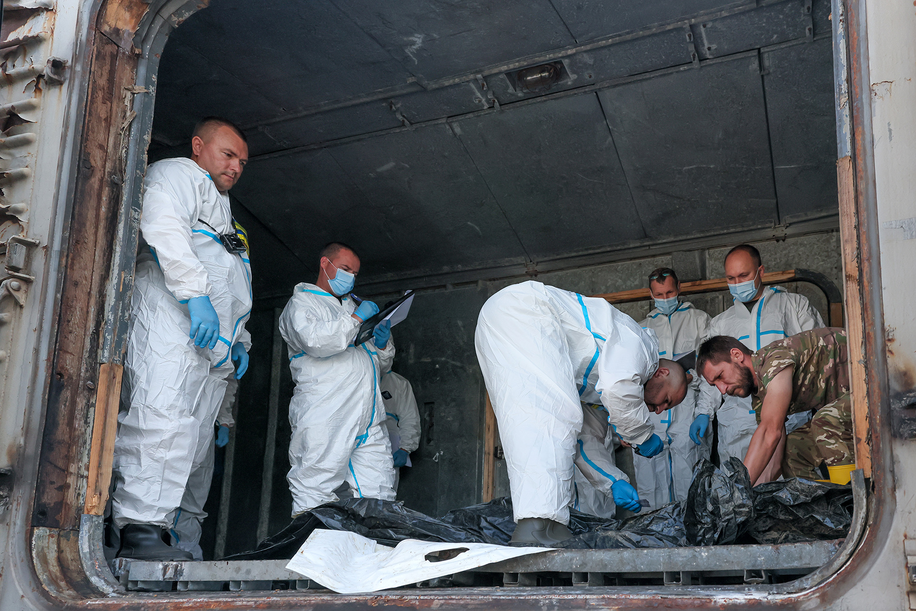 Криміналісти та працівники центру розшуку осіб, безвісти зниклих за особливих обставин, ГУНП в Запорізькій області здійснюють первинний огляд репатрійованих тіл полеглих українських захисників. Серпень 2025 року.