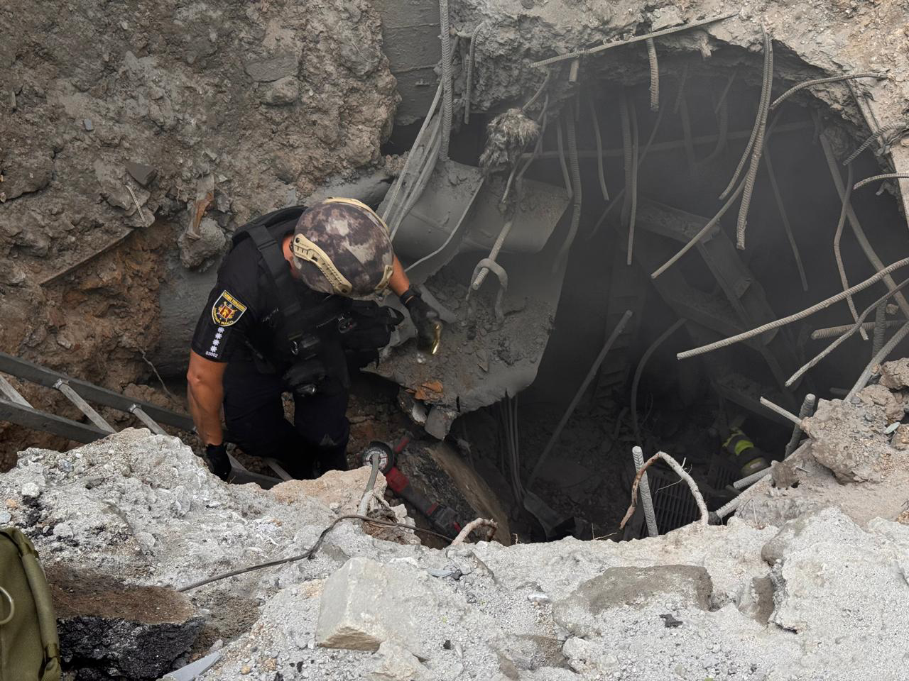 Поліцейський допомагає рятувальникам дістати важкопоранену людину з-під завалів будівлі, розбитої російською ракетою «Іскандер-К». Серпень 2025 року.