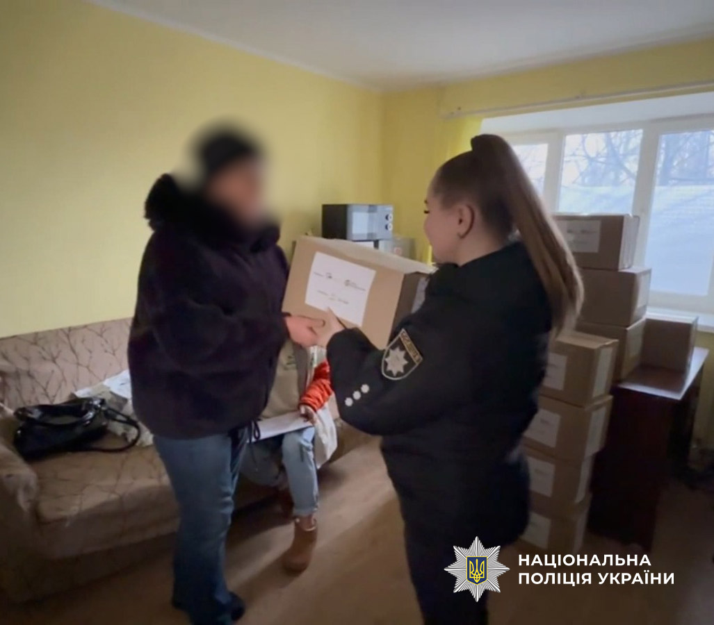поліцейська вручає коробку із допомогою