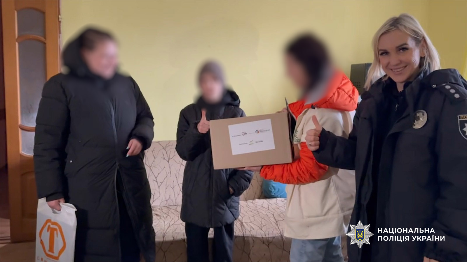 поліцейська вручає коробку із допомогою
