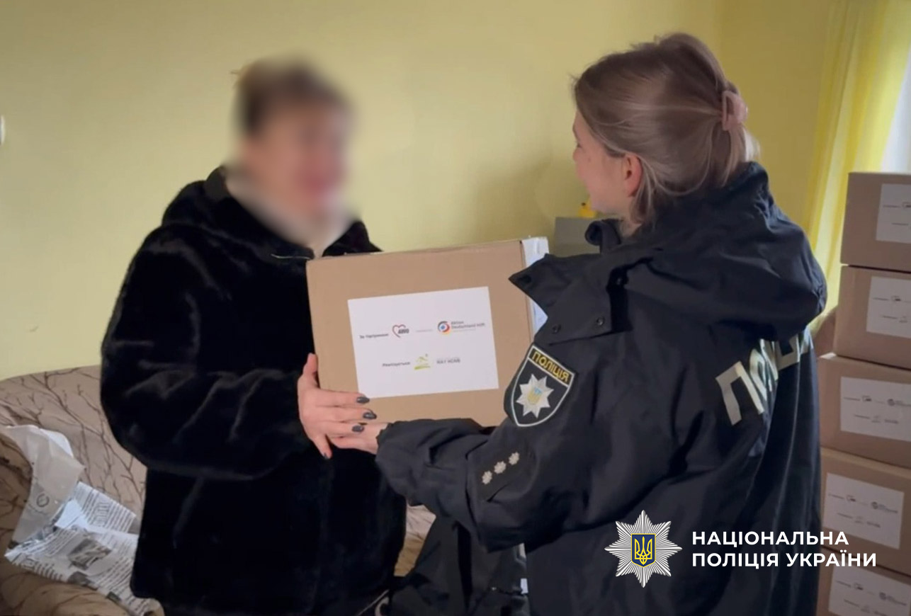 поліцейська вручає коробку із допомогою