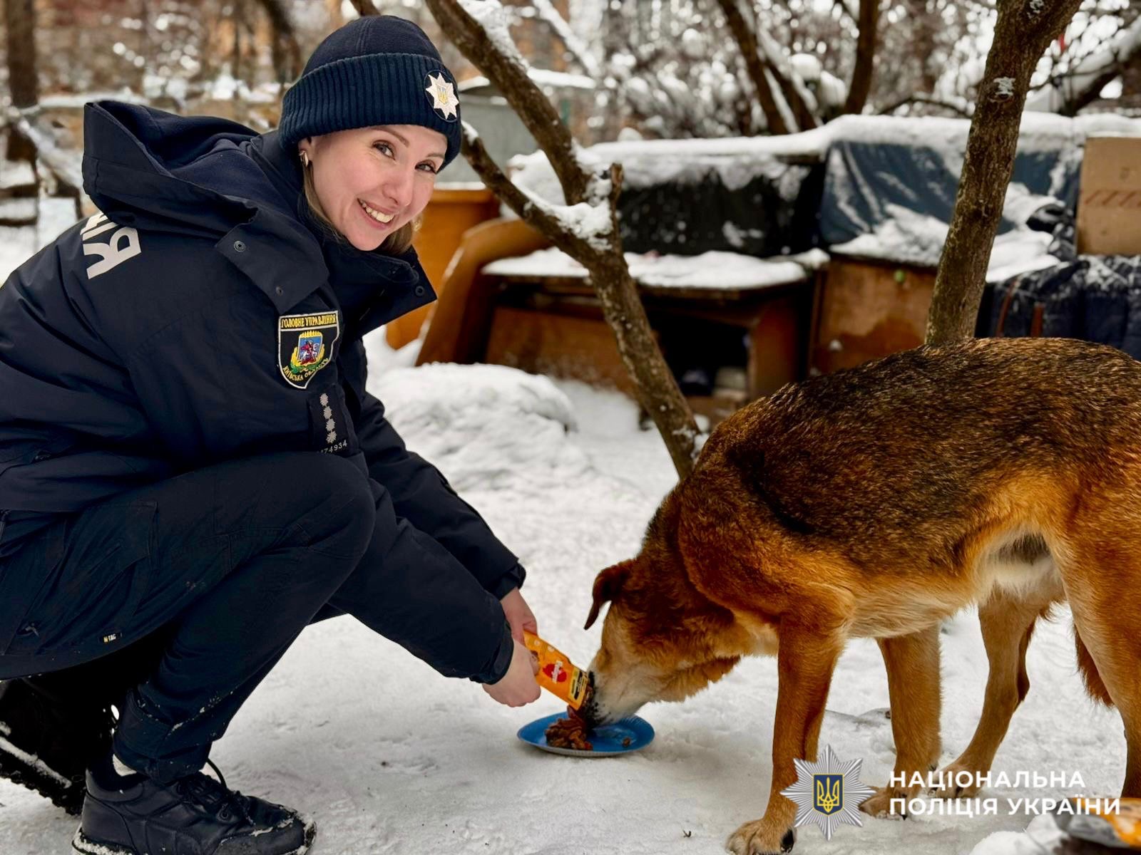 На фото зображена поліцейська, яка годує песика