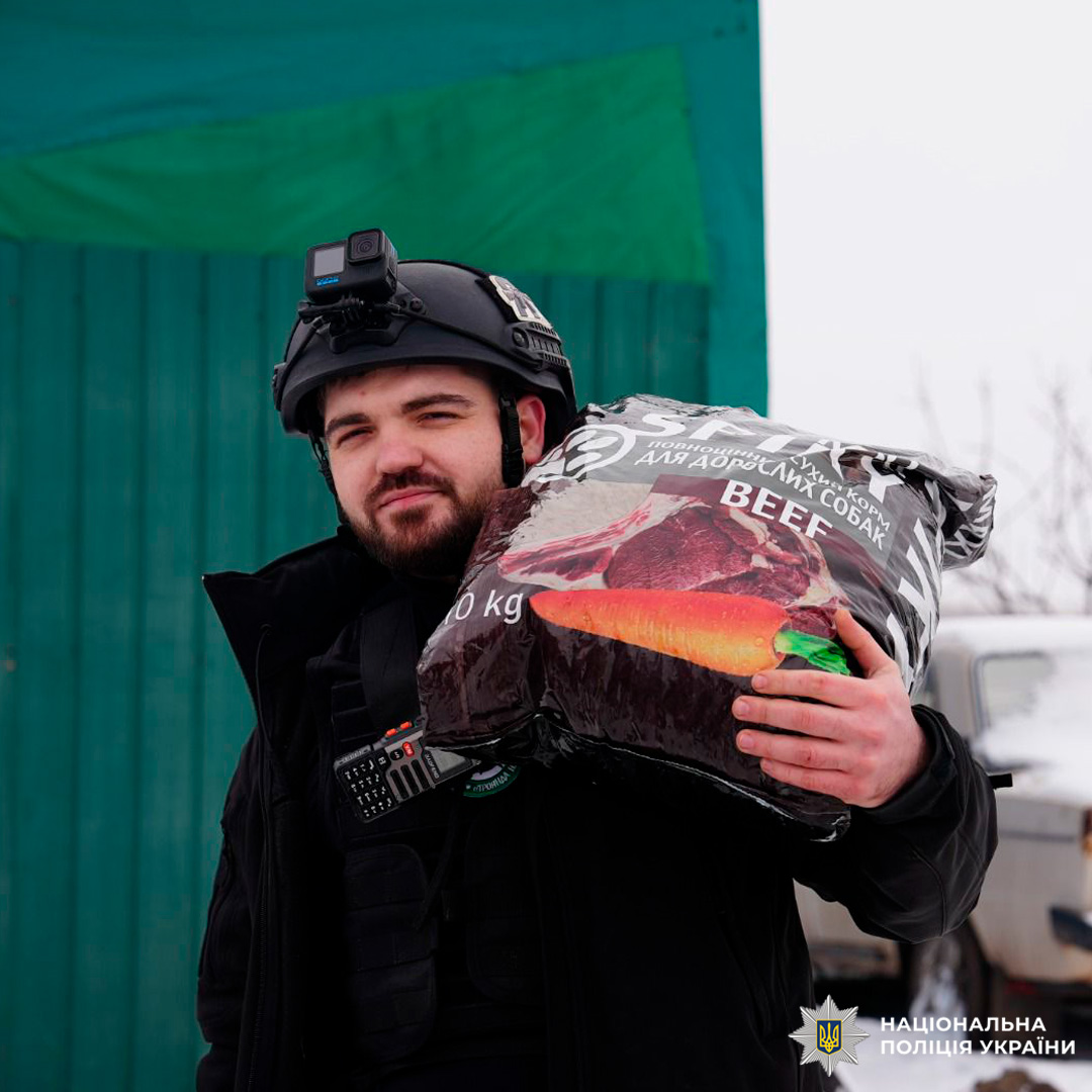Співробітник поліції доставляє 10 кг корму для дорослих собак у зимових умовах.