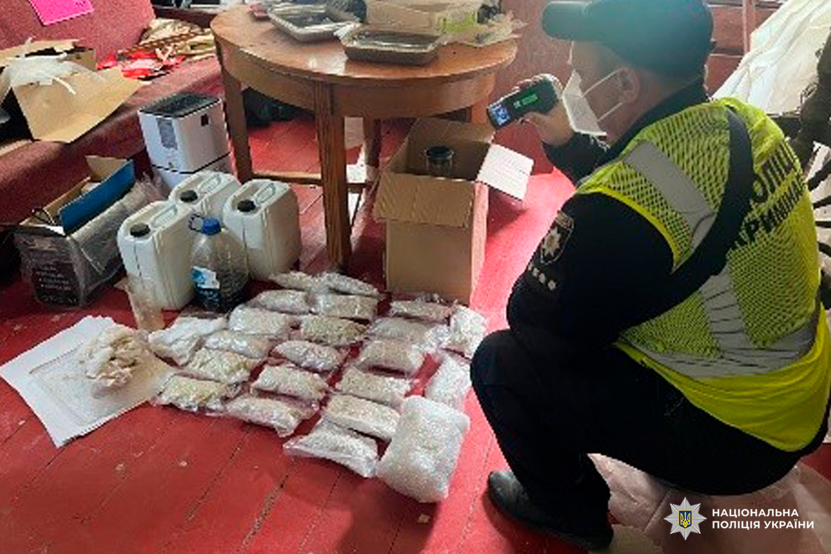 Поліцейський України документує вилучені пакети з порошкоподібними речовинами та хімічні контейнери.