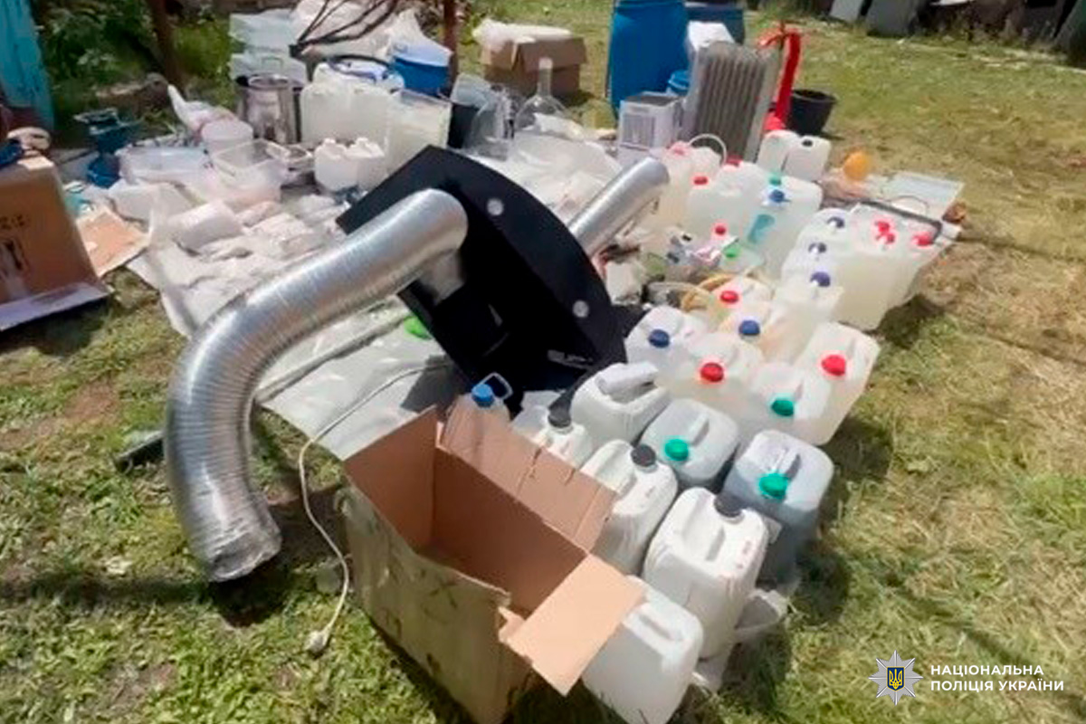 Вилучені поліцією України пластикові каністри та обладнання, розташовані на відкритій території.