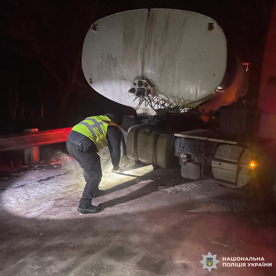 Нічна допомога автоцистерни: поліцейський оглядає транспортний засіб із ліхтарем.