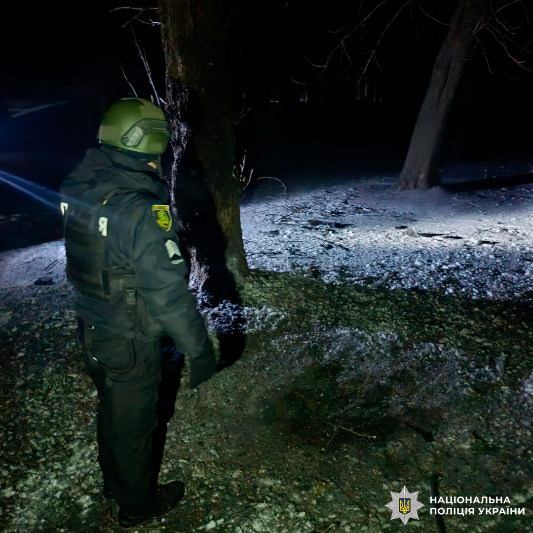 Поліцейський у тактичному спорядженні проводить нічний огляд місцевості з ліхтарем