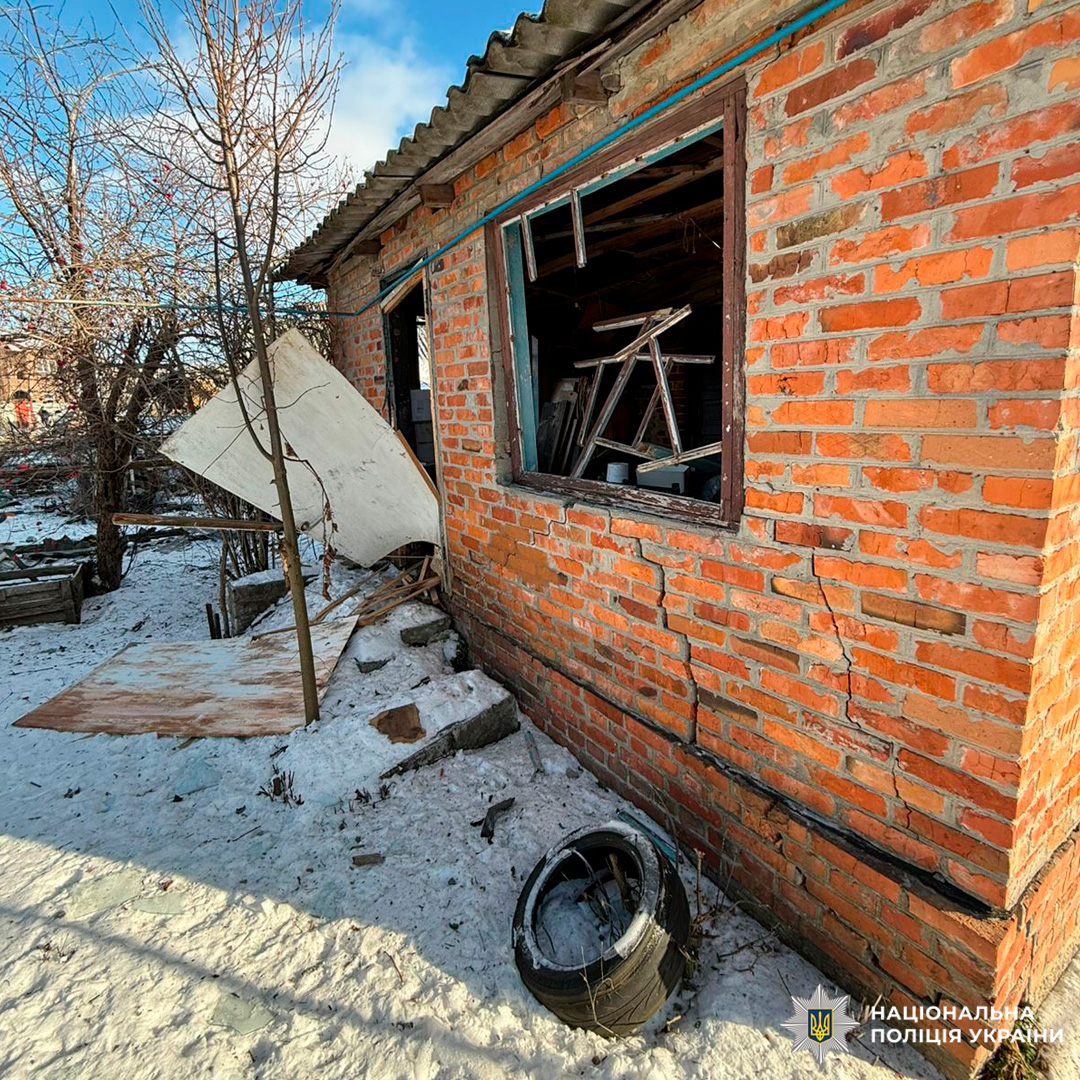 Пошкоджена цегляна будівля з тріщинами на стіні та уламками на подвір’ї