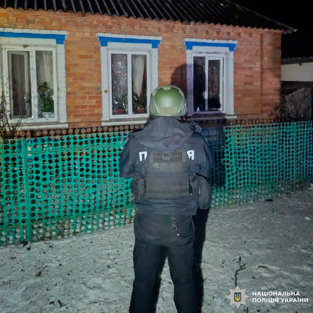 Поліцейський у тактичному спорядженні проводить нічну операцію біля приватного будинку