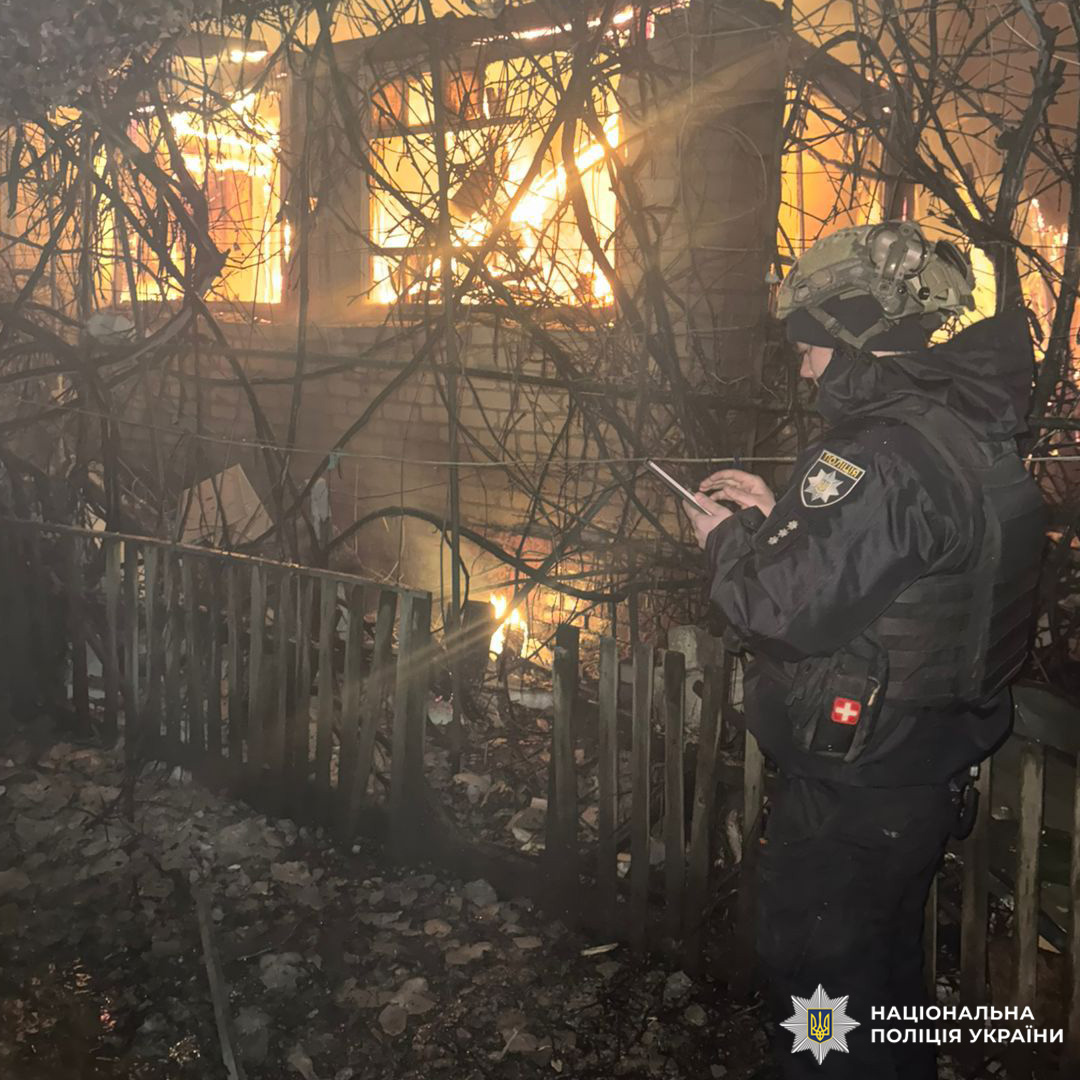 Співробітник Нацполіції у тактичному спорядженні фіксує дані біля будівлі, охопленої нічною пожежею.