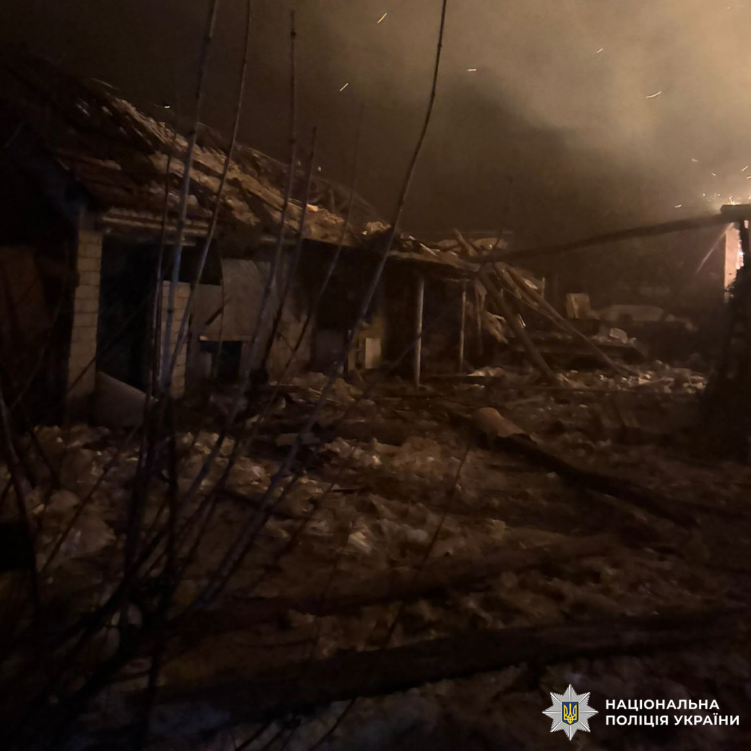 Зруйновані будівлі з обваленими дахами та стінами, навколо розкидані уламки й дим.