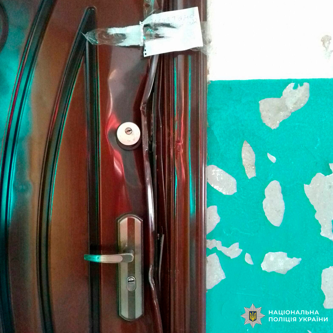 Сліди насильного проникнення: двері зігнуті біля замка, метал деформований, а на стіні видно стару фарбу.