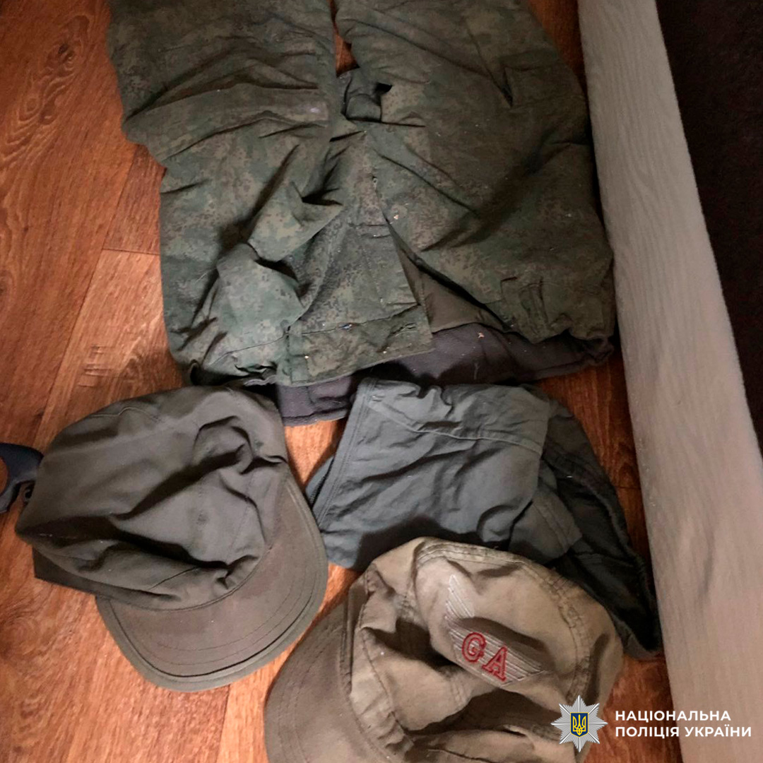 Військовий одяг на підлозі: камуфляж і кепки.