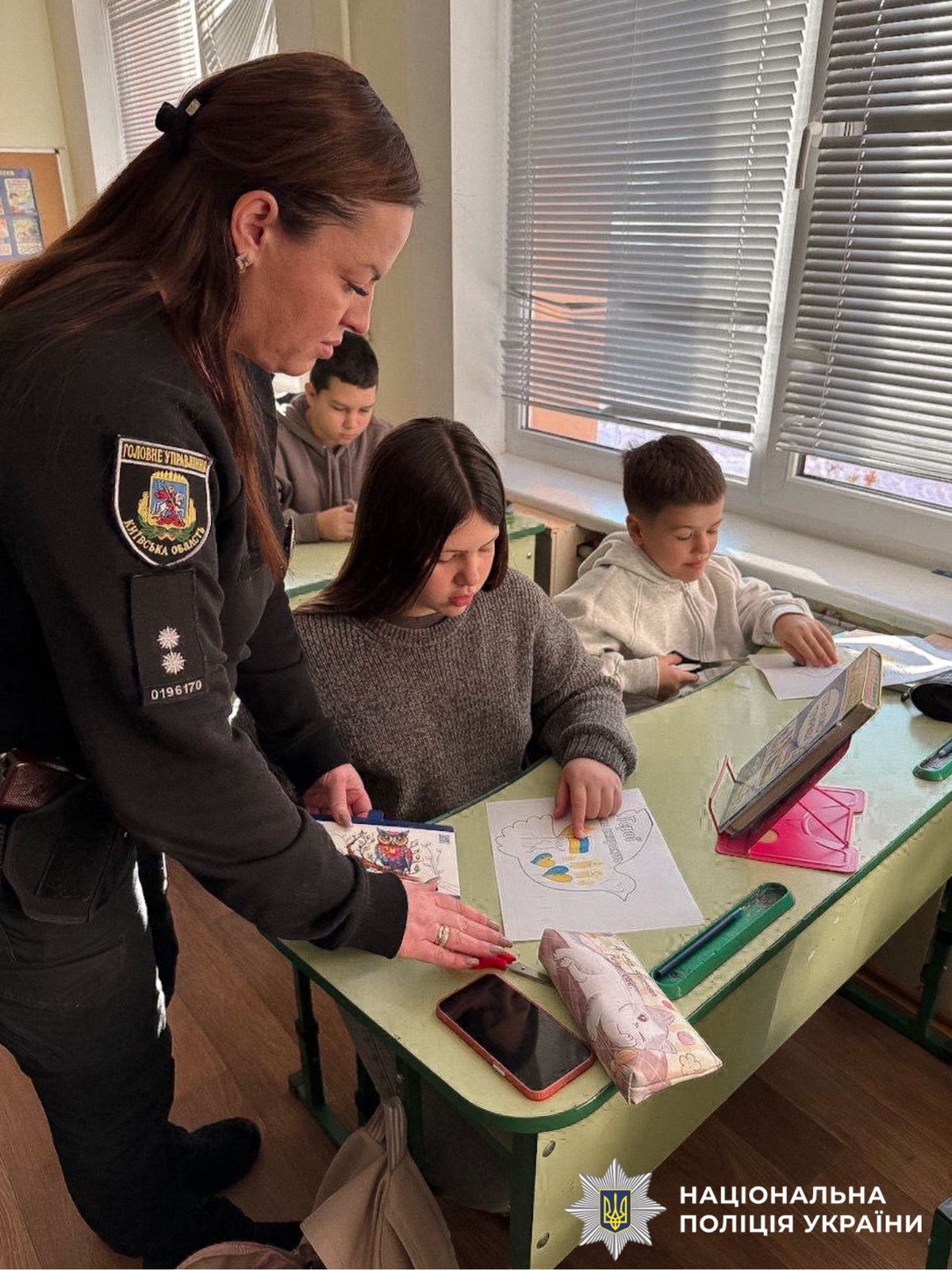 На фотографії зображена поліцейська, яка спільно з дітьми до дня Героїв Небесної Сотні виготовляла паперових ангелів.