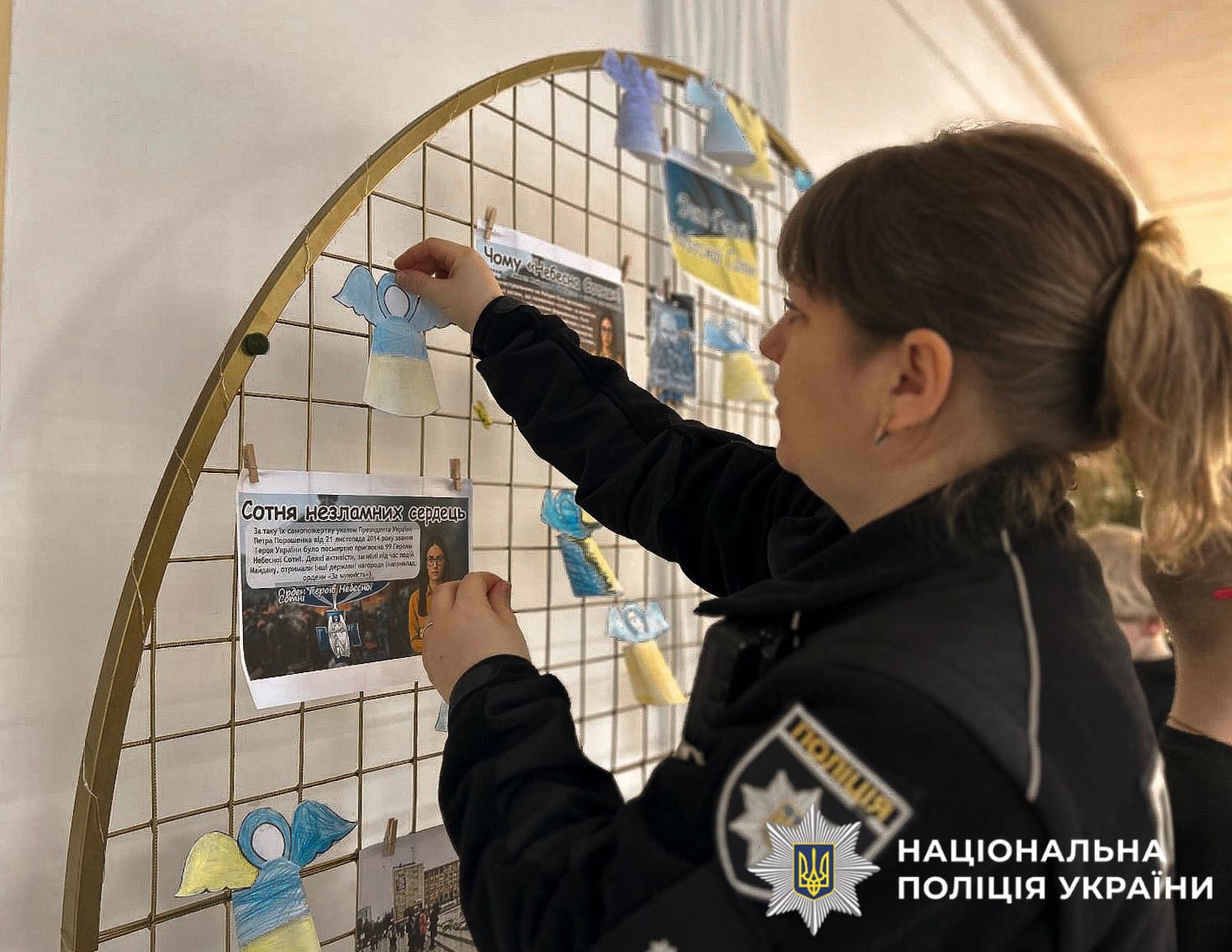 На фотографії зображена поліцейська, яка спільно з дітьми до дня Героїв Небесної Сотні виготовляла паперових ангелів.
