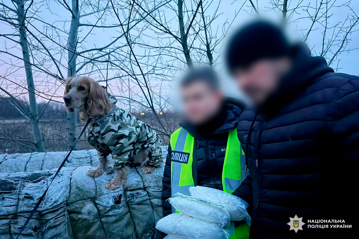 Поліцейський із вилученими пакетами речовини та службовий собака під час операції Національної поліції України.