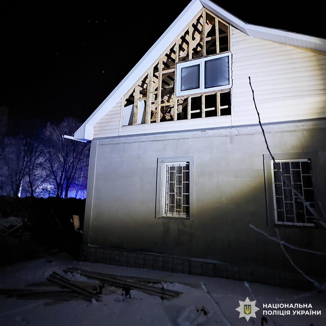 Пошкоджений житловий будинок у Харківській області вночі. Верхній поверх має зруйновані стіни та відкриті дерев’яні конструкції.