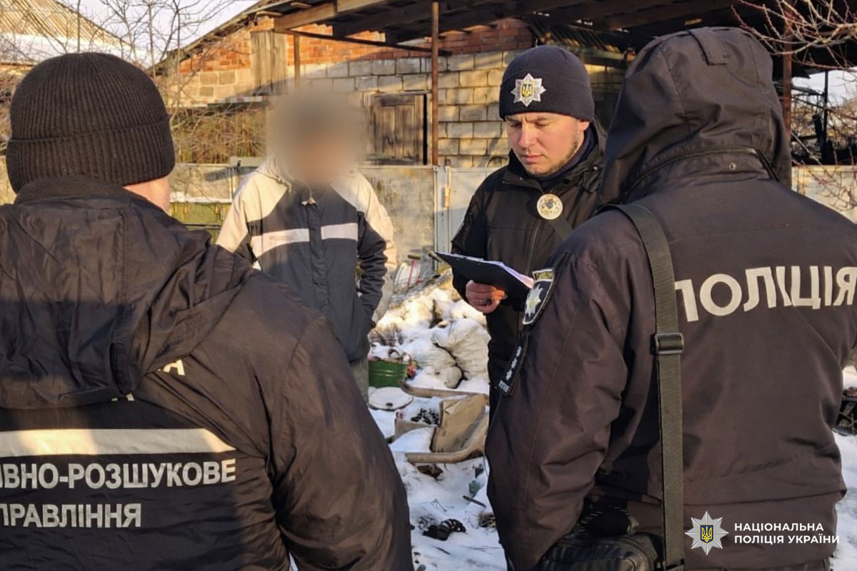 Працівники поліції проводять опитування громадянина на засніженій території біля будівлі.