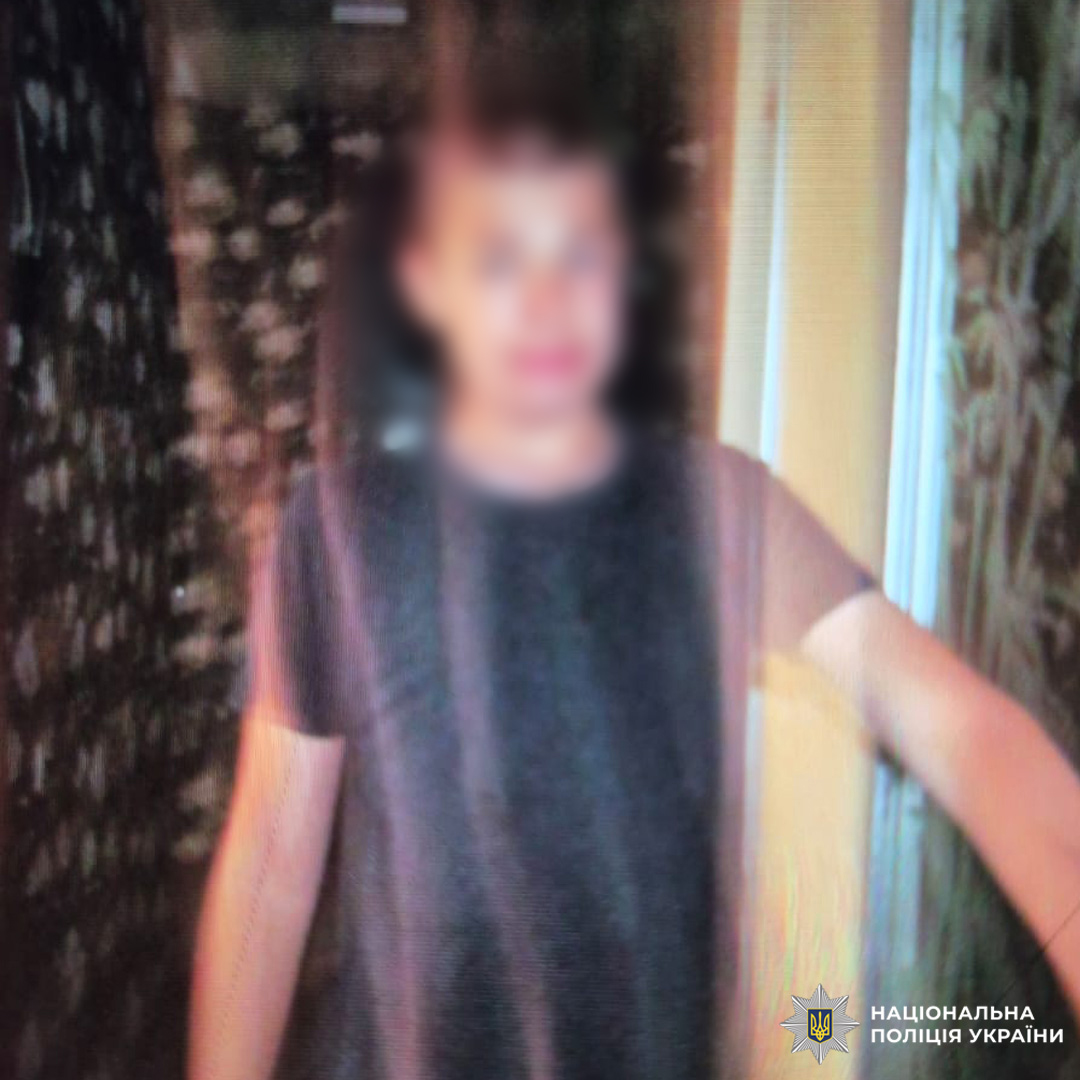 Фото молодої людини у темній футболці біля дверей, фон зі шпалерами, легке розмиття.