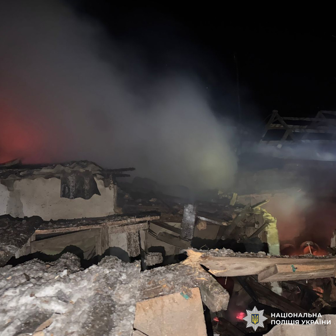 Зруйновані та обгорілі будівельні конструкції з димом у нічний час.