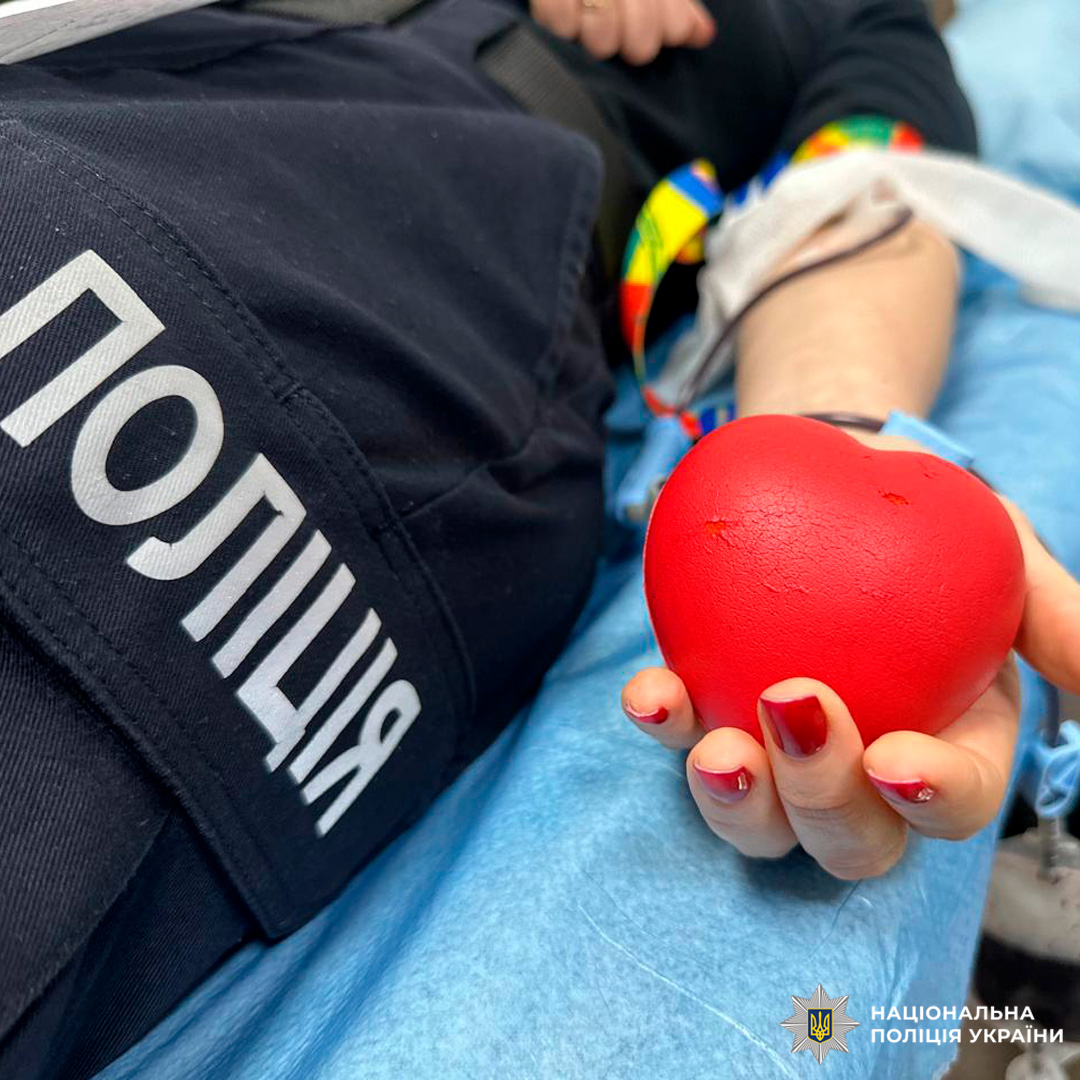 Співробітник Національної поліції України бере участь у донорстві крові, лежачи на медичному ліжку з джгутом на руці.