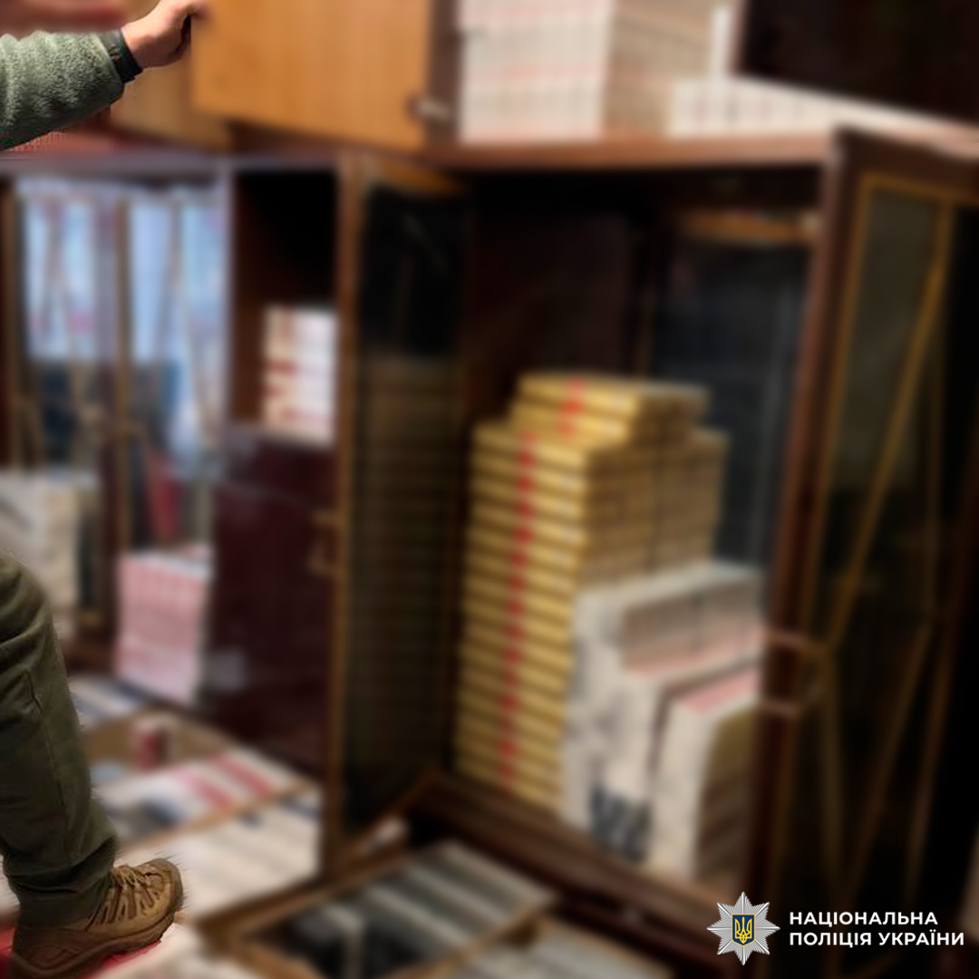 Приміщення зі схованими тютюновими виробами: відкриті шафи та коробки заповнені блоками сигарет різних марок.