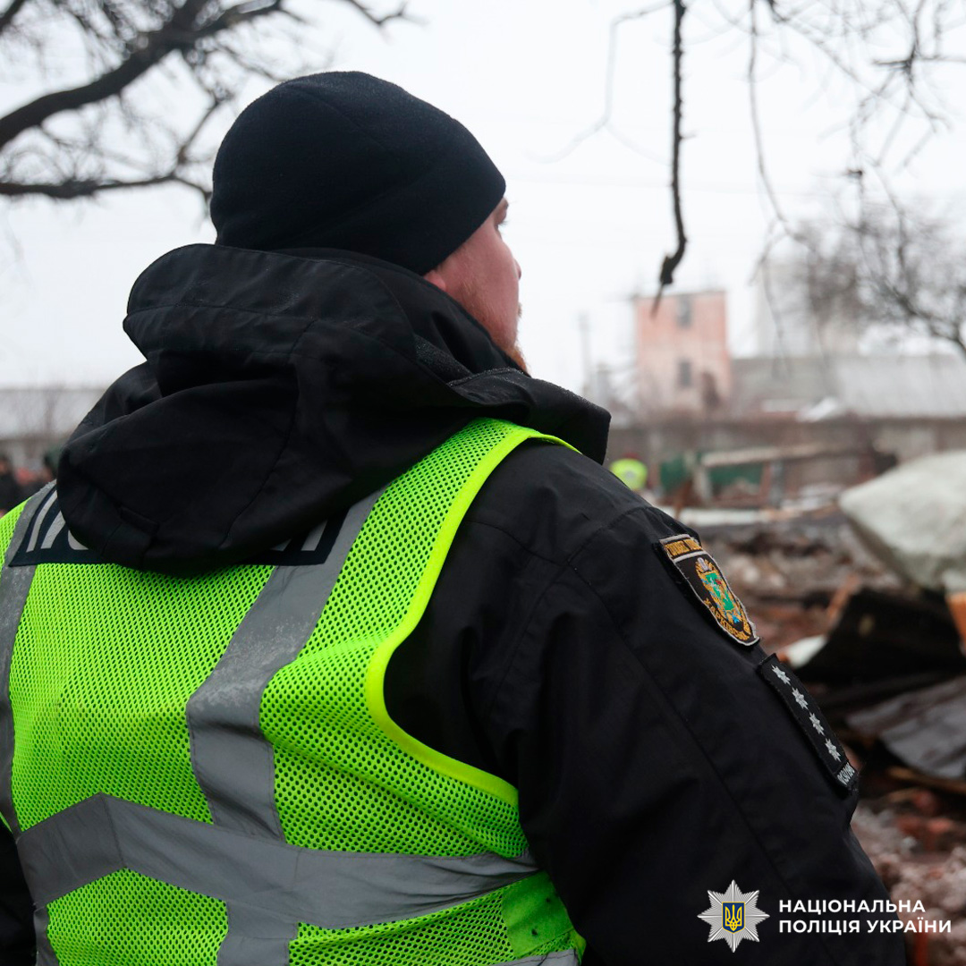 Поліцейський документує наслідки інциденту серед пошкоджених споруд у зимових умовах.